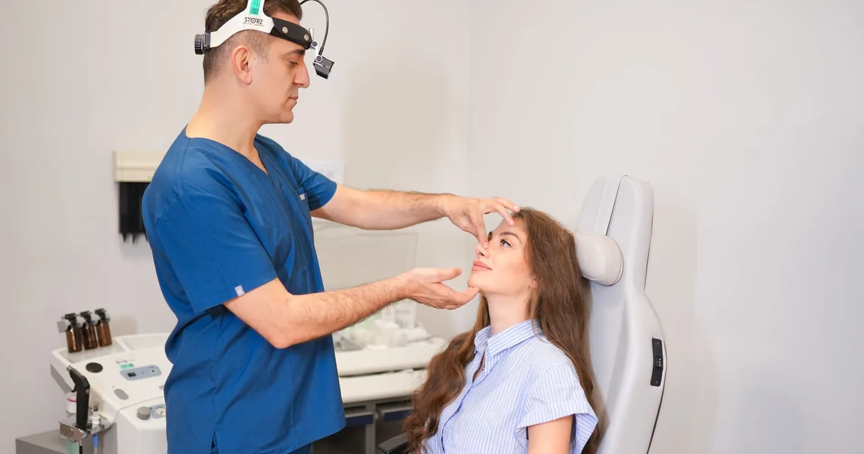 Cirurgião plástico examinando uma paciente em consulta no consultório