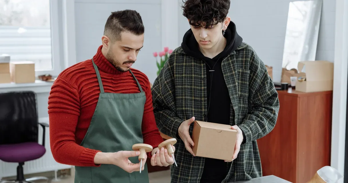 Dois homens examinando um produto e a embalagem de papelão